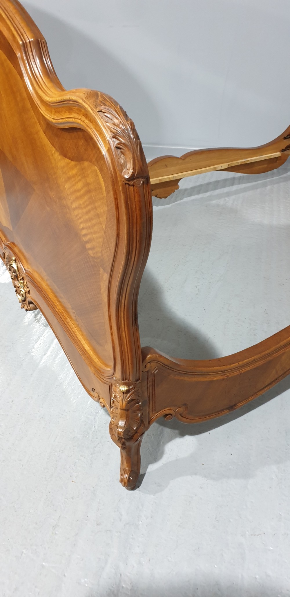 A French Louis XV style walnut bed frame featuring quarter-matched veneered panels and parcel gilt hand-carved cresting on the headboard and footboard. View XIII