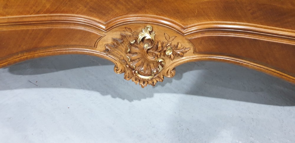 A French Louis XV style walnut bed frame featuring quarter-matched veneered panels and parcel gilt hand-carved cresting on the headboard and footboard. View XIV