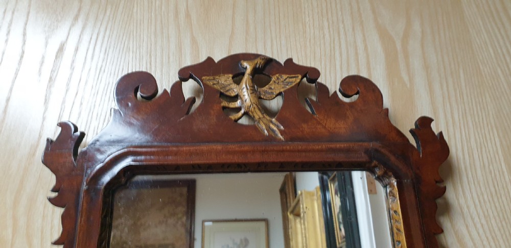 A Georgian mahogany fretwork wall mirror featuring a scrolled frame, a gilded bird motif at the top crest, and a gilded inner border. View V