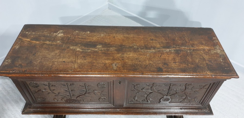 A dark brown carved wood Italian cassone coffer featuring two foliate relief panels and carved lion paw feet. View V