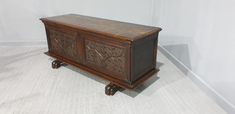 A dark brown carved wood Italian cassone coffer featuring two foliate relief panels and carved lion paw feet. View VIII