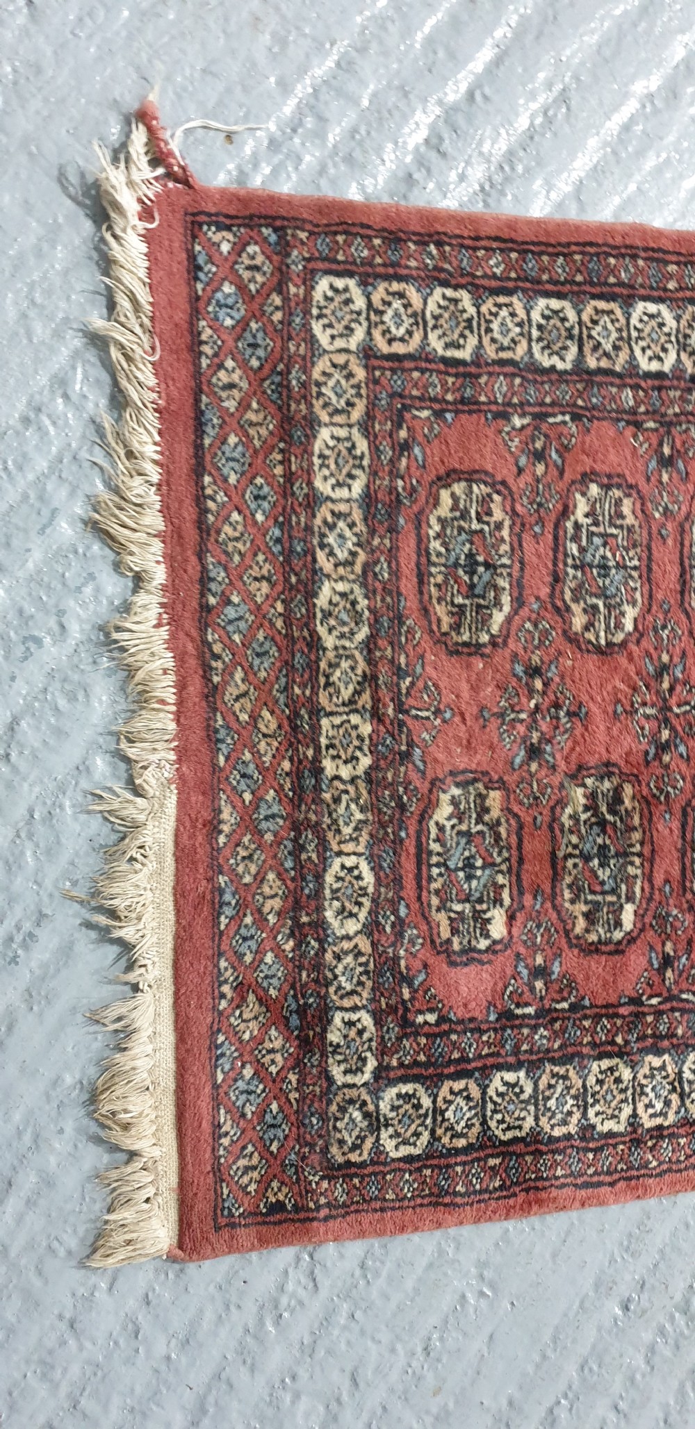 An extra-long hand-knotted wool carpet runner featuring repeated geometric medallion patterns on a terracotta red field with patterned cream borders. View IX