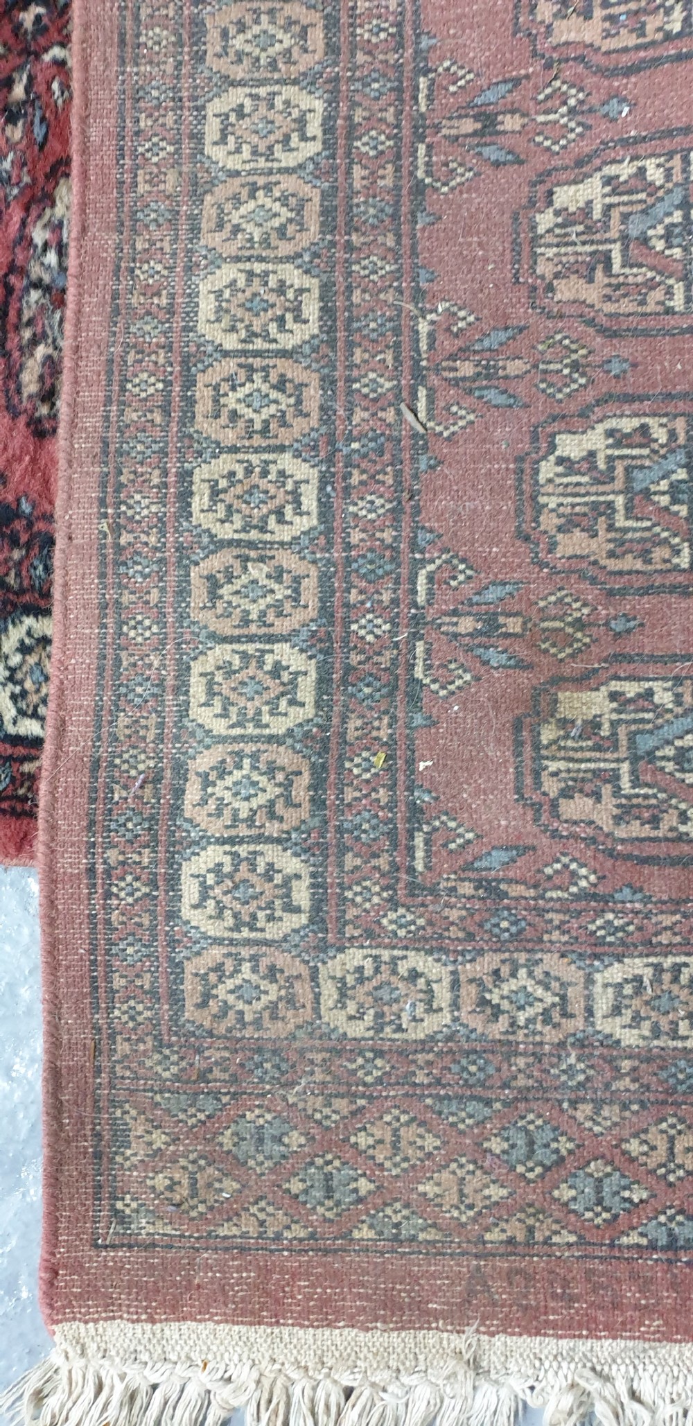 An extra-long hand-knotted wool carpet runner featuring repeated geometric medallion patterns on a terracotta red field with patterned cream borders. View X