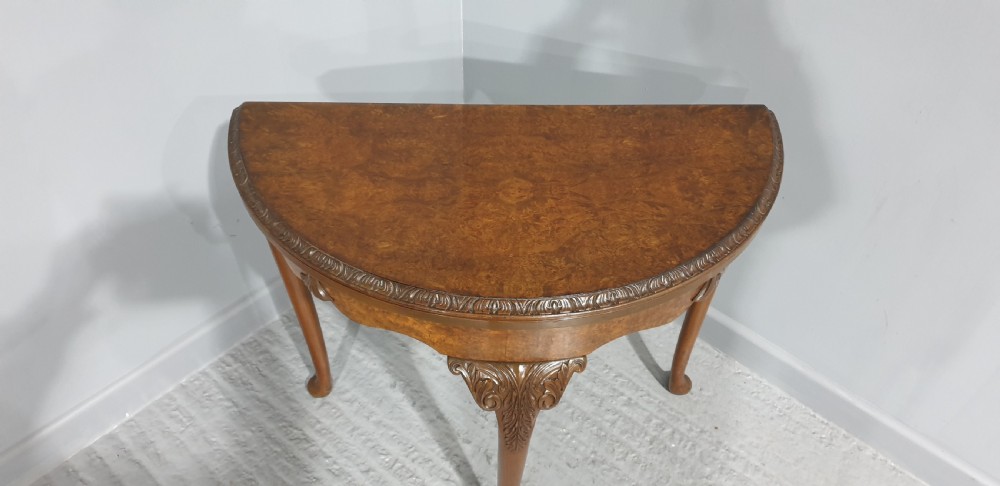 A semi-circular burr walnut games table with a fold-over top, carved edge moulding, and cabriole legs featuring carved knees and pad feet. View III