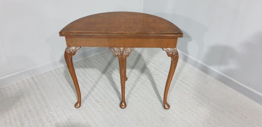 A semi-circular burr walnut games table with a fold-over top, carved edge moulding, and cabriole legs featuring carved knees and pad feet. View IV