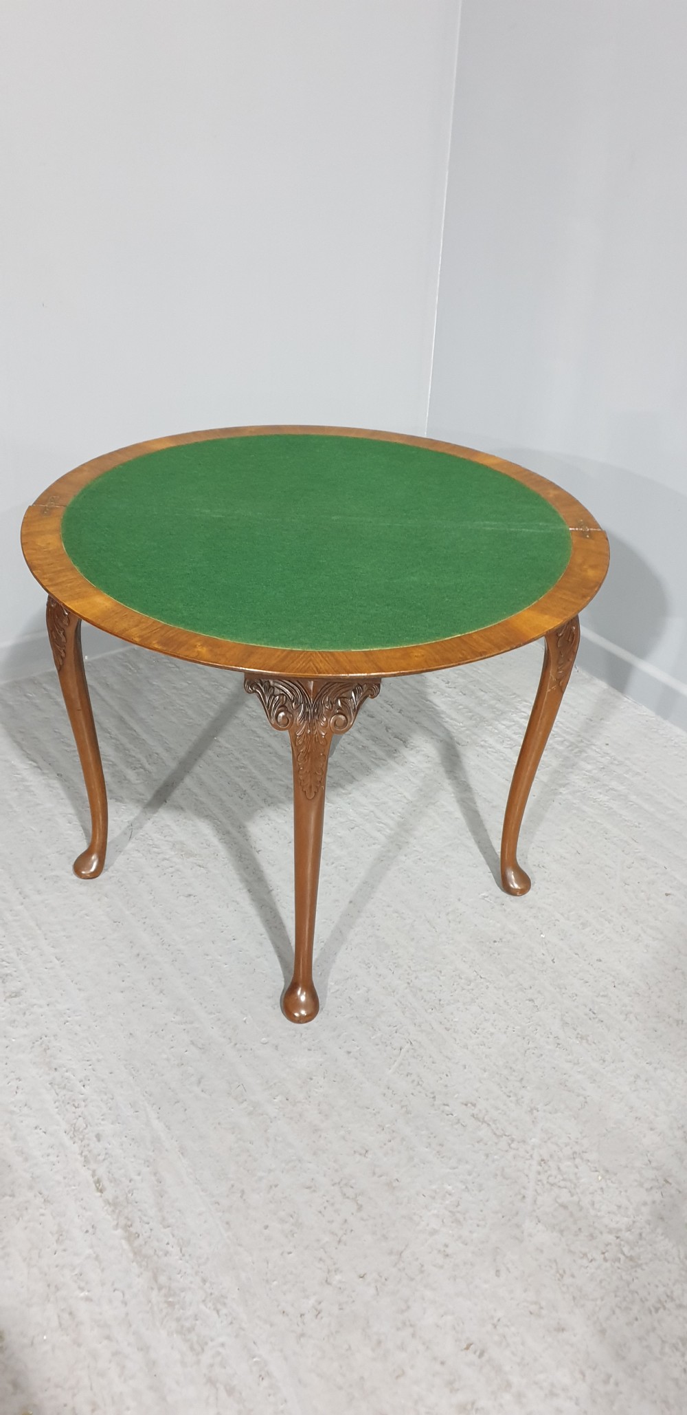 A semi-circular burr walnut games table with a fold-over top, carved edge moulding, and cabriole legs featuring carved knees and pad feet. View VI