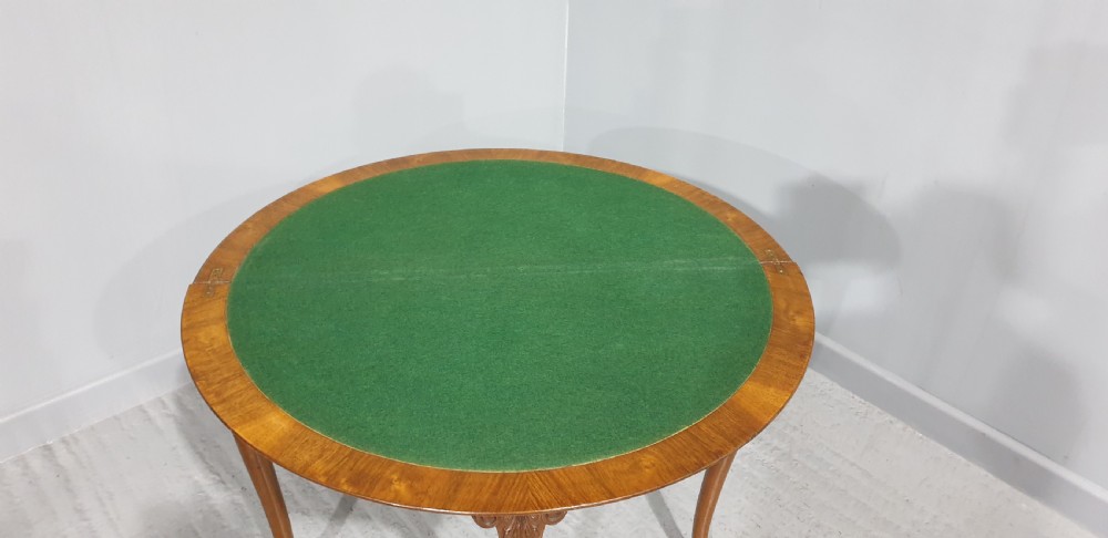 A semi-circular burr walnut games table with a fold-over top, carved edge moulding, and cabriole legs featuring carved knees and pad feet. View VII