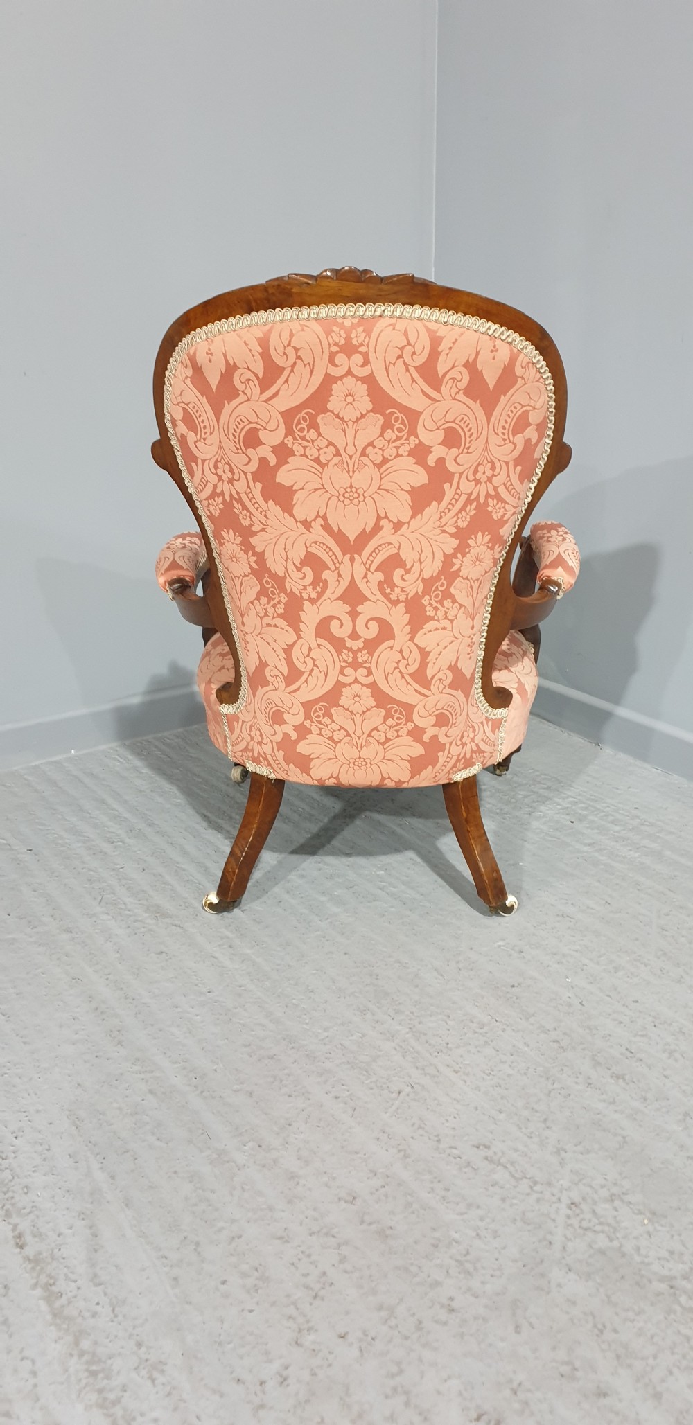 A Victorian carved mahogany armchair featuring button-tufted peach damask upholstery, scroll arms, and cabriole legs with castors. View XI