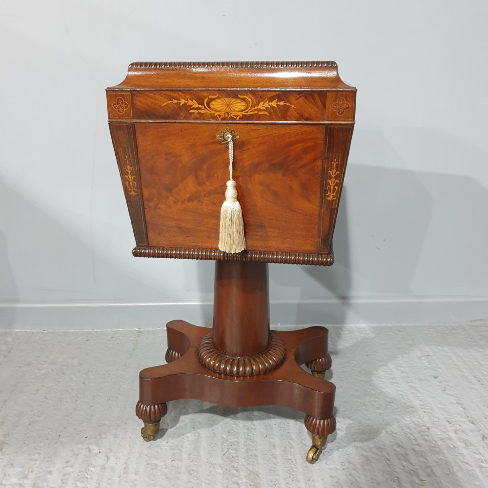 A William IV mahogany pedestal wine cellarette with marquetry inlay, gadrooned trim, and a quadform base on brass castors.