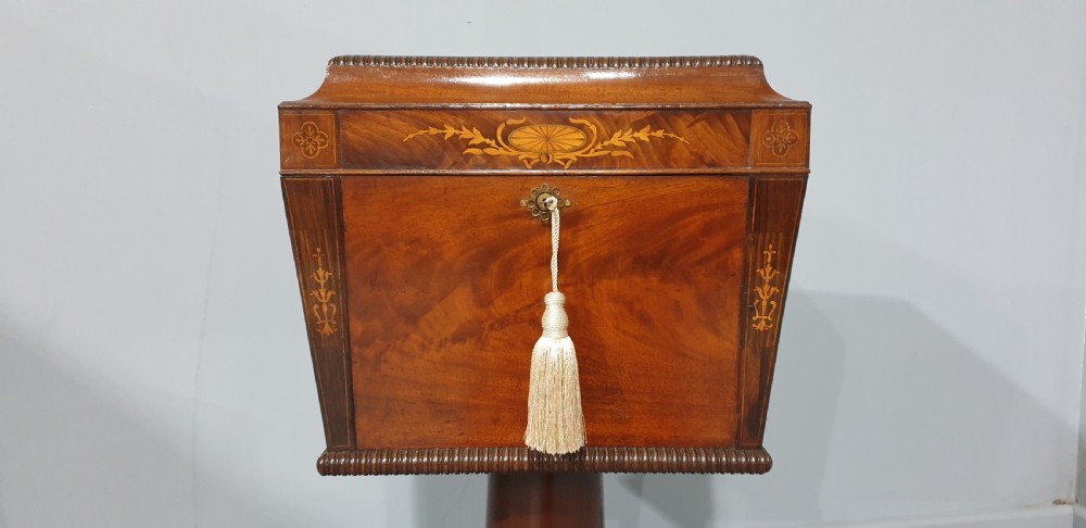 A William IV mahogany pedestal wine cellarette with marquetry inlay, gadrooned trim, and a quadform base on brass castors. View IV