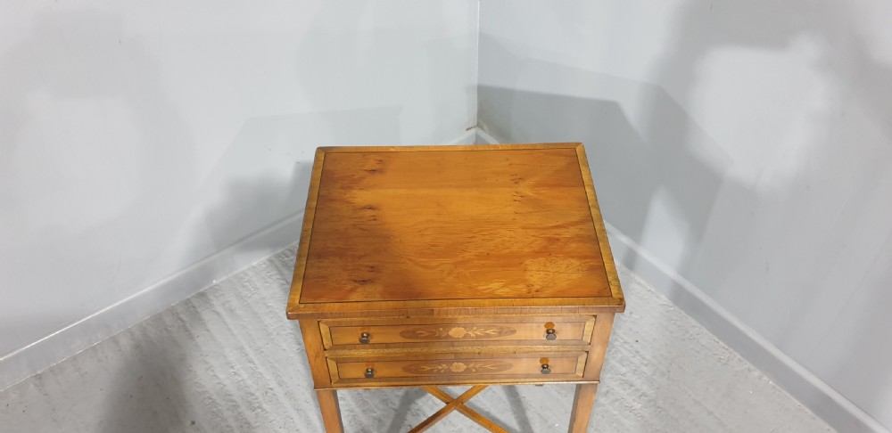 A tall yew wood side table featuring two drawers adorned with oval floral marquetry inlays, slim square legs, and an X-frame stretcher base. View V
