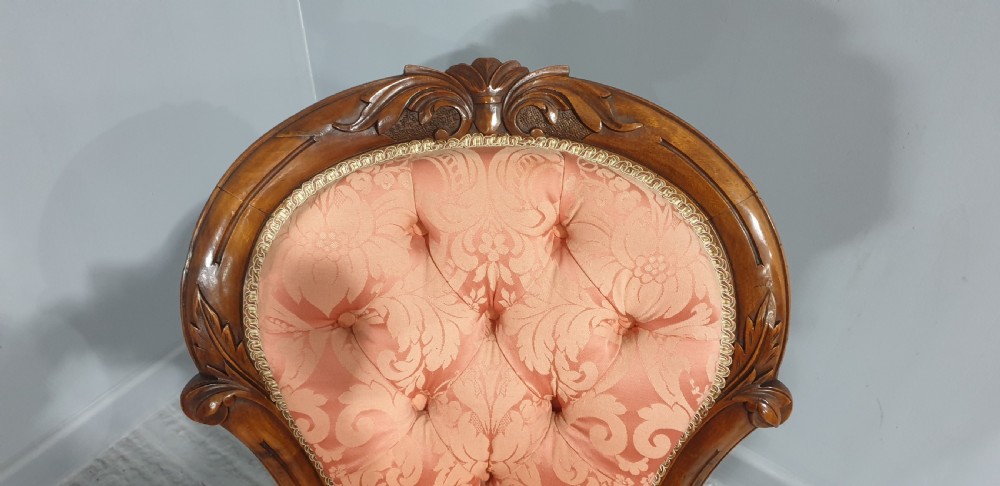 A Victorian mahogany nursing chair with button-backed peach damask upholstery and carved cabriole legs on ceramic castors. View VII