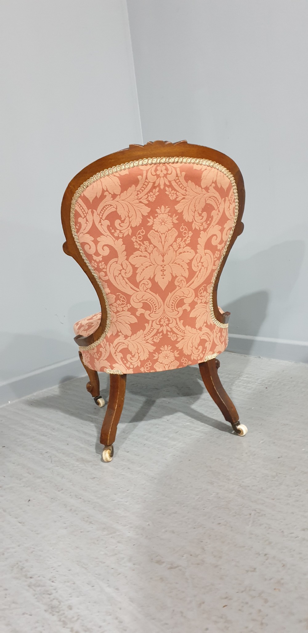 A Victorian mahogany nursing chair with button-backed peach damask upholstery and carved cabriole legs on ceramic castors. View IX