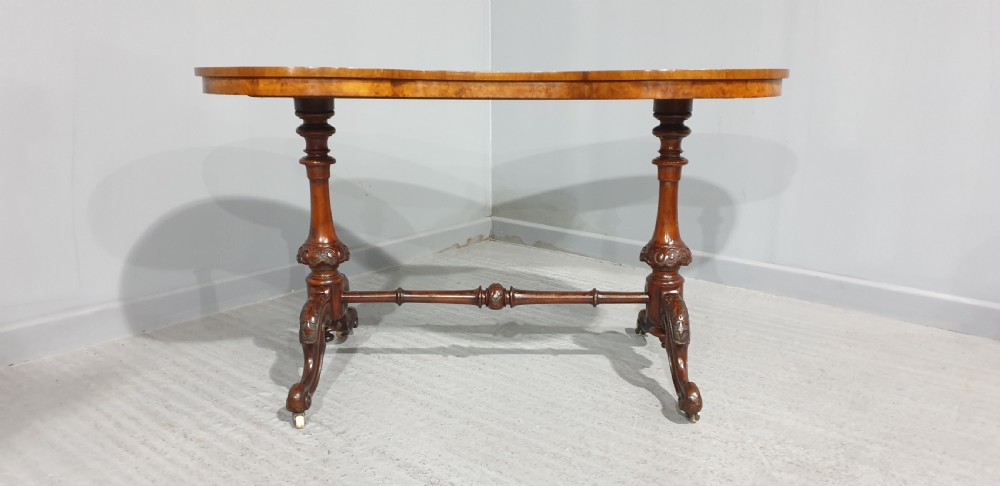 A Victorian kidney-shaped writing desk crafted from burr walnut with a green leather inset top and carved turned legs joined by a stretcher. View VI