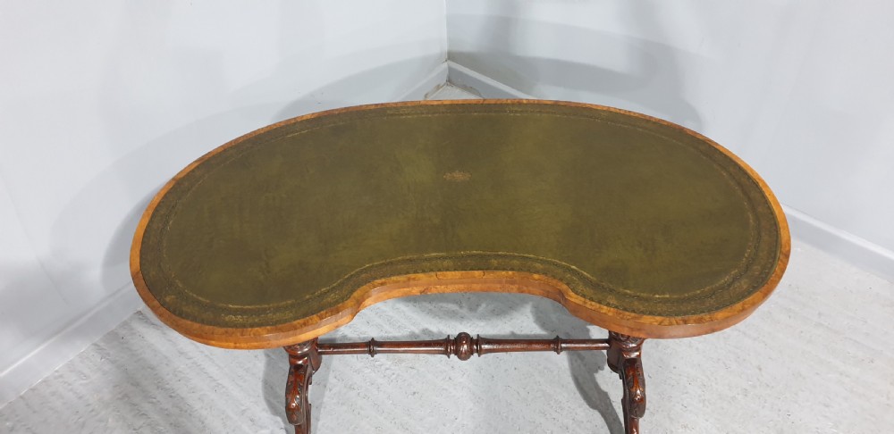 A Victorian kidney-shaped writing desk crafted from burr walnut with a green leather inset top and carved turned legs joined by a stretcher. View VII