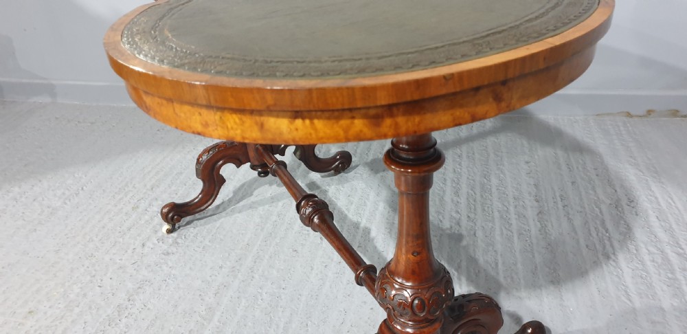 A Victorian kidney-shaped writing desk crafted from burr walnut with a green leather inset top and carved turned legs joined by a stretcher. View X