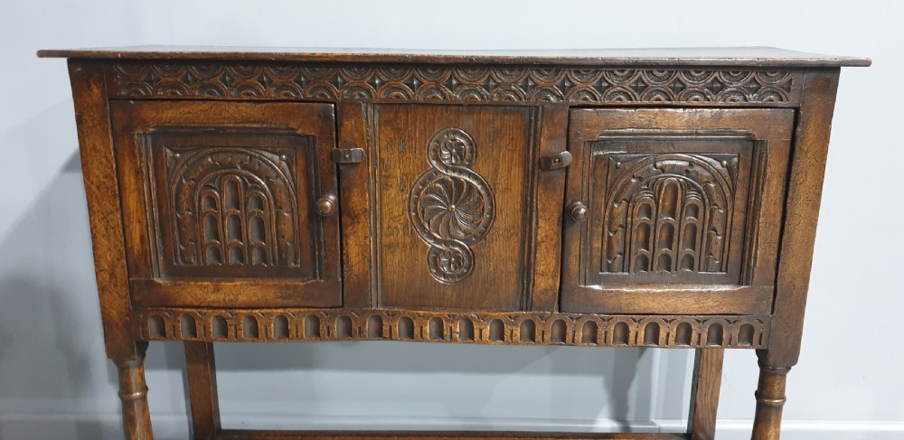 A small dark oak carved sideboard with two decorative panelled doors, turned legs, and lower stretchers. View II