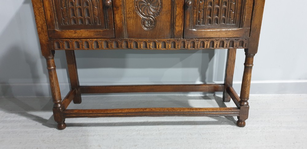 A small dark oak carved sideboard with two decorative panelled doors, turned legs, and lower stretchers. View III