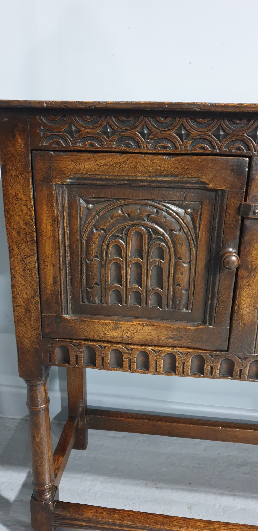 A small dark oak carved sideboard with two decorative panelled doors, turned legs, and lower stretchers. View XIII
