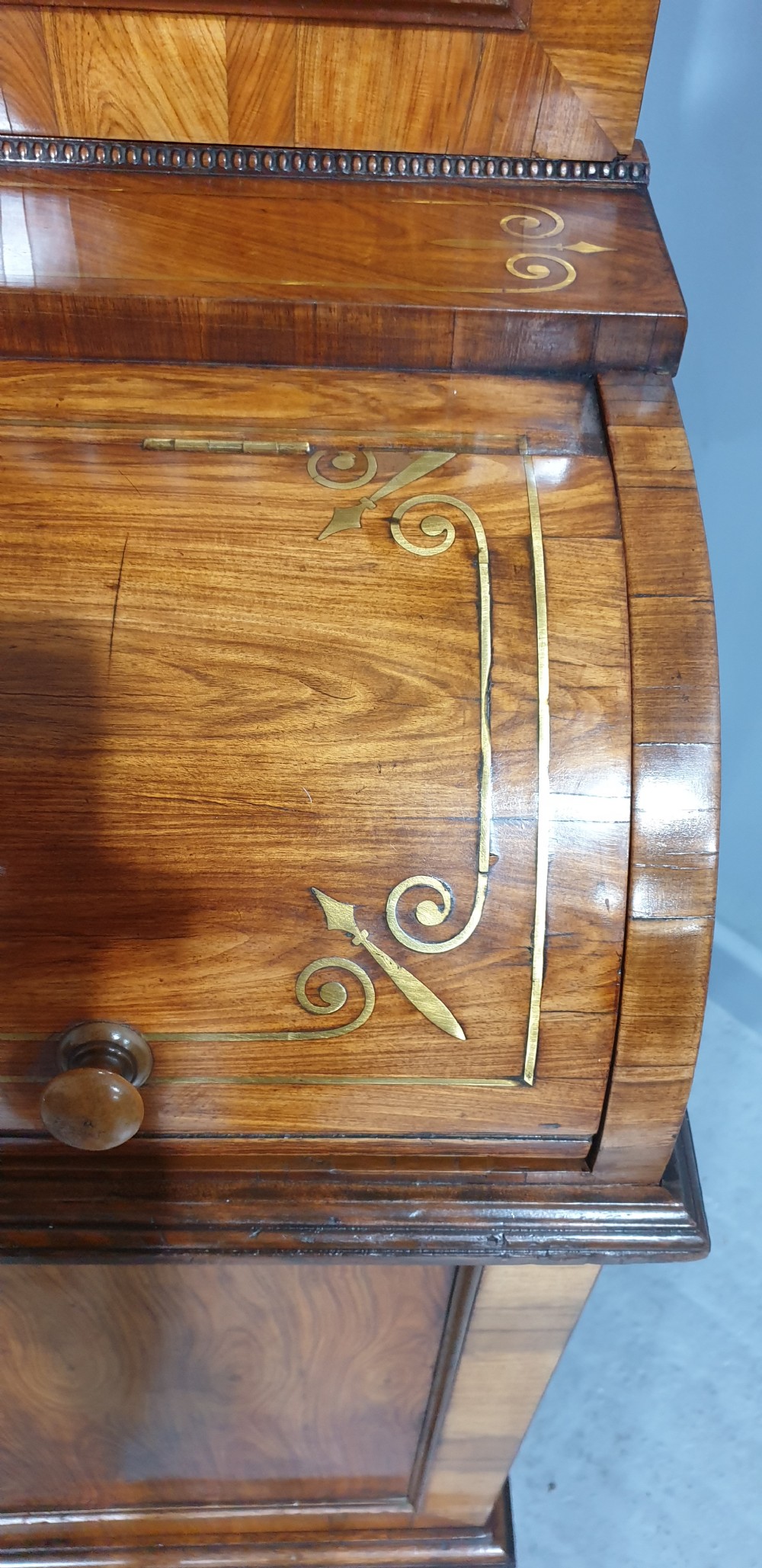 A Regency rosewood bureau bookcase featuring a scrolled pediment with brass finials, glazed upper display doors, a roll-top cylinder writing section with brass inlay, and a twin-door lower cupboard. View XIV