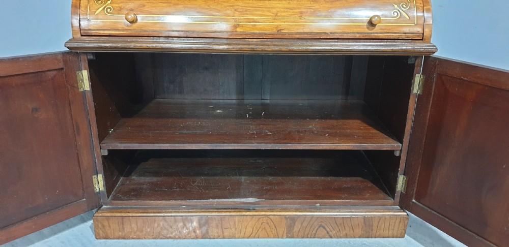 A Regency rosewood bureau bookcase featuring a scrolled pediment with brass finials, glazed upper display doors, a roll-top cylinder writing section with brass inlay, and a twin-door lower cupboard. View XVIII