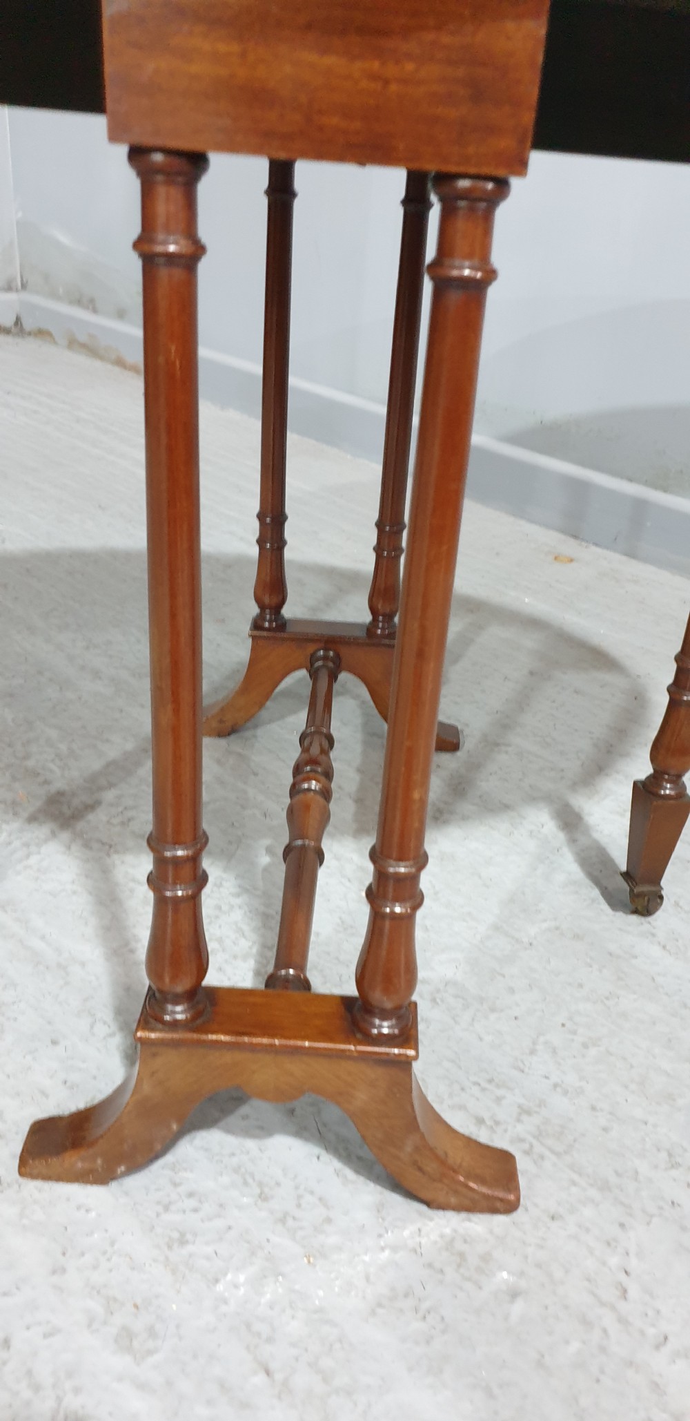 An Edwardian mahogany baby Sutherland drop-leaf table featuring an oval top with satinwood crossbanding, central marquetry patera, slender turned legs, and brass casters. View VII