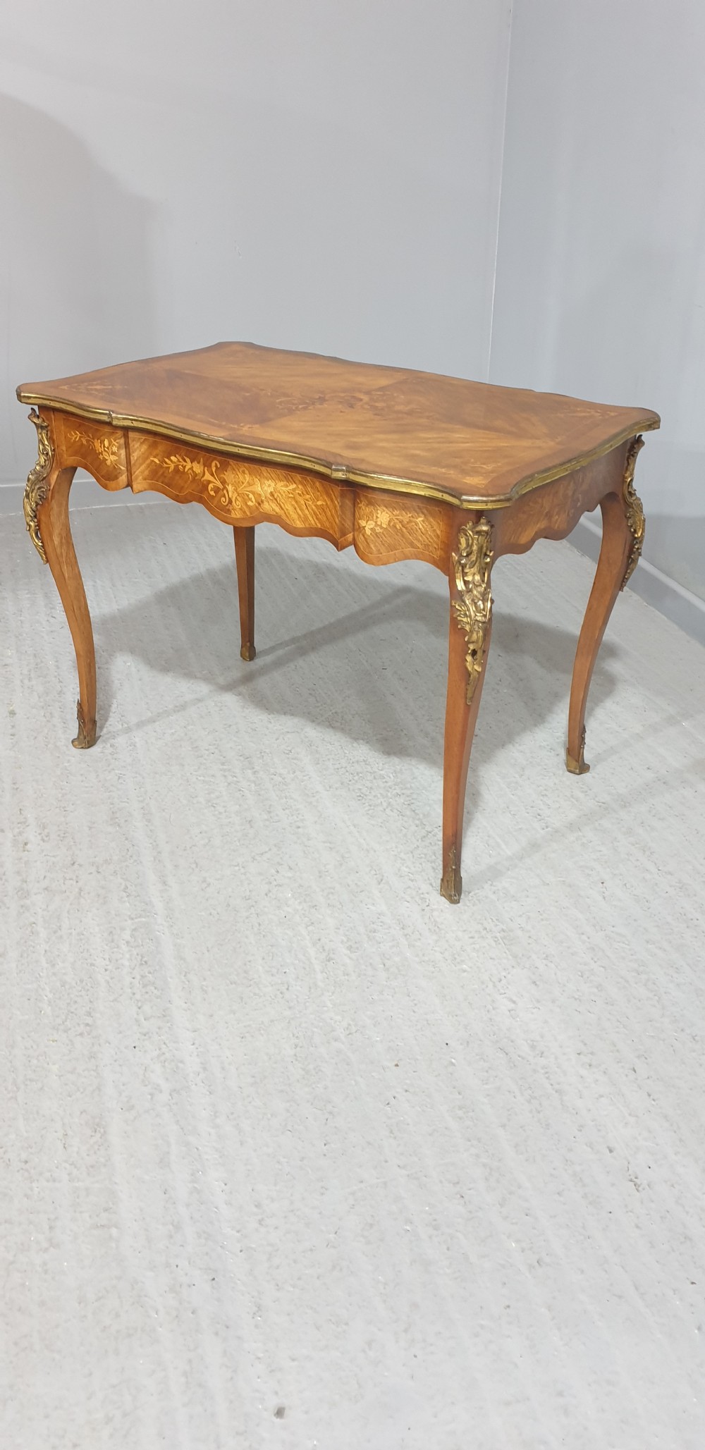 A French Louis XV style bureau plat decorated with floral marquetry inlay, curved cabriole legs, and ornate gilt bronze mounts. View III