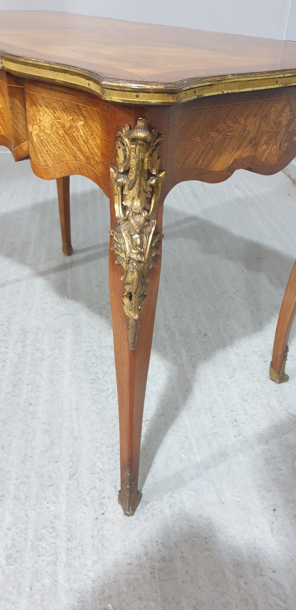A French Louis XV style bureau plat decorated with floral marquetry inlay, curved cabriole legs, and ornate gilt bronze mounts. View VI