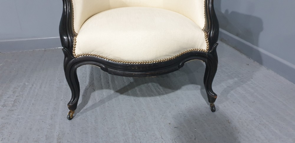 Victorian ebonised spoon-back armchair with off-white upholstery, brass castors, and cabriole legs. View IV