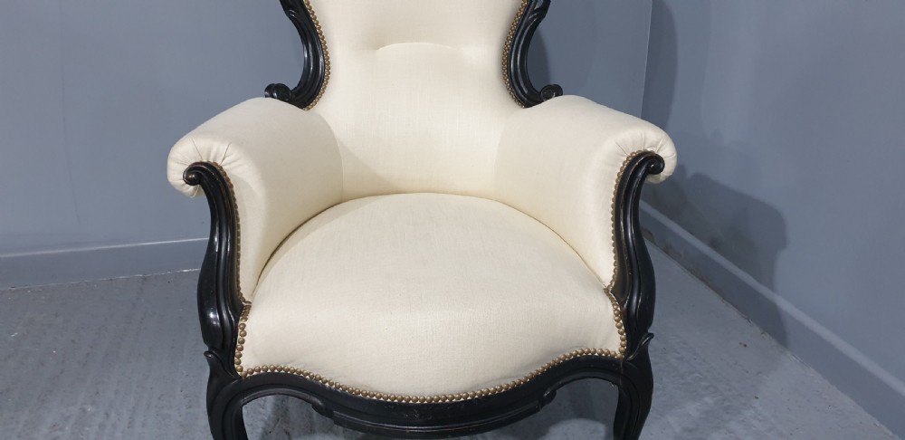Victorian ebonised spoon-back armchair with off-white upholstery, brass castors, and cabriole legs. View V