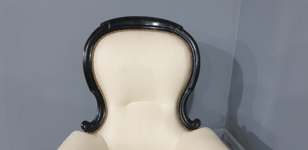 Victorian ebonised spoon-back armchair with off-white upholstery, brass castors, and cabriole legs. View VII