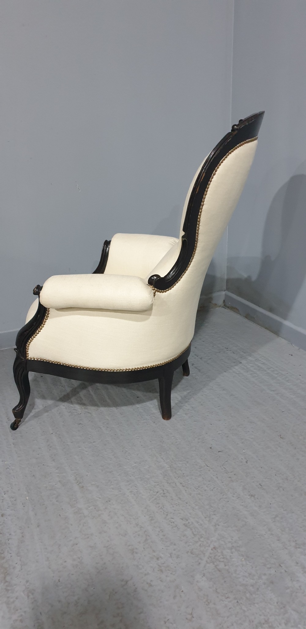 Victorian ebonised spoon-back armchair with off-white upholstery, brass castors, and cabriole legs. View VIII