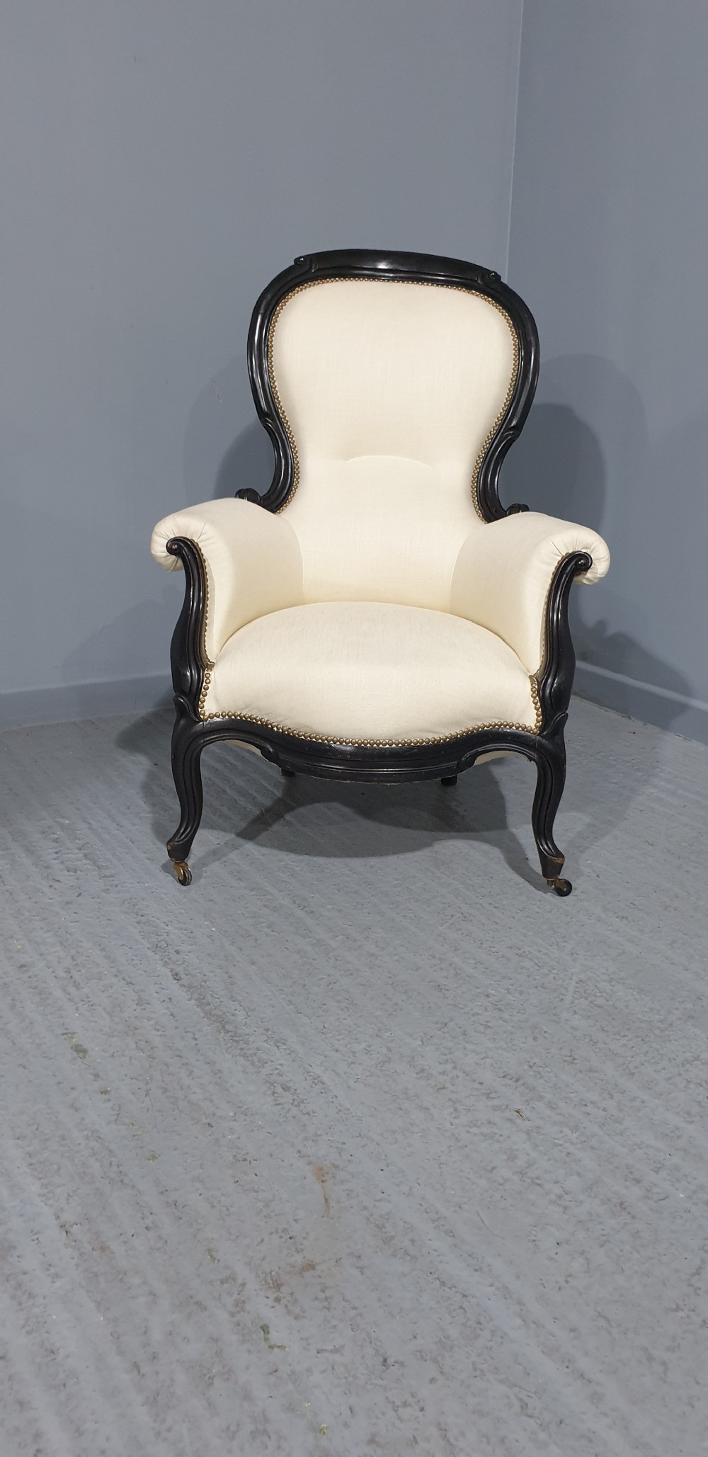 Victorian ebonised spoon-back armchair with off-white upholstery, brass castors, and cabriole legs. View XII