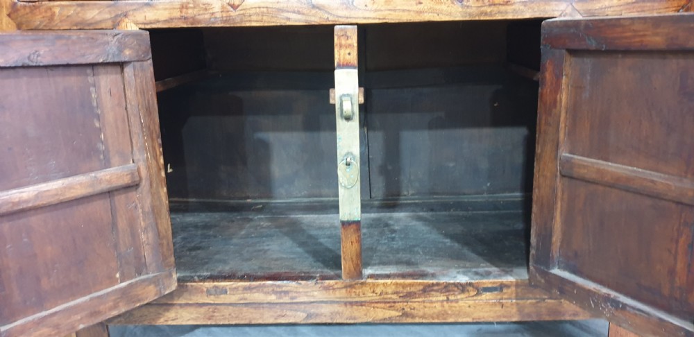 A 19th-century Chinese elm sideboard featuring three upper drawers, two panelled cupboard doors with a central circular brass lockplate, and additional small side drawers with brass fittings. View IX