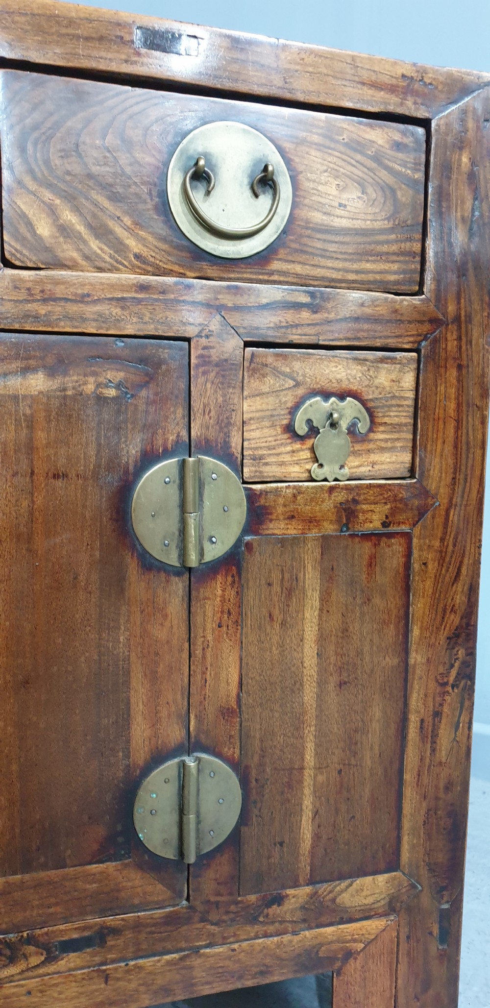 A 19th-century Chinese elm sideboard featuring three upper drawers, two panelled cupboard doors with a central circular brass lockplate, and additional small side drawers with brass fittings. View XI