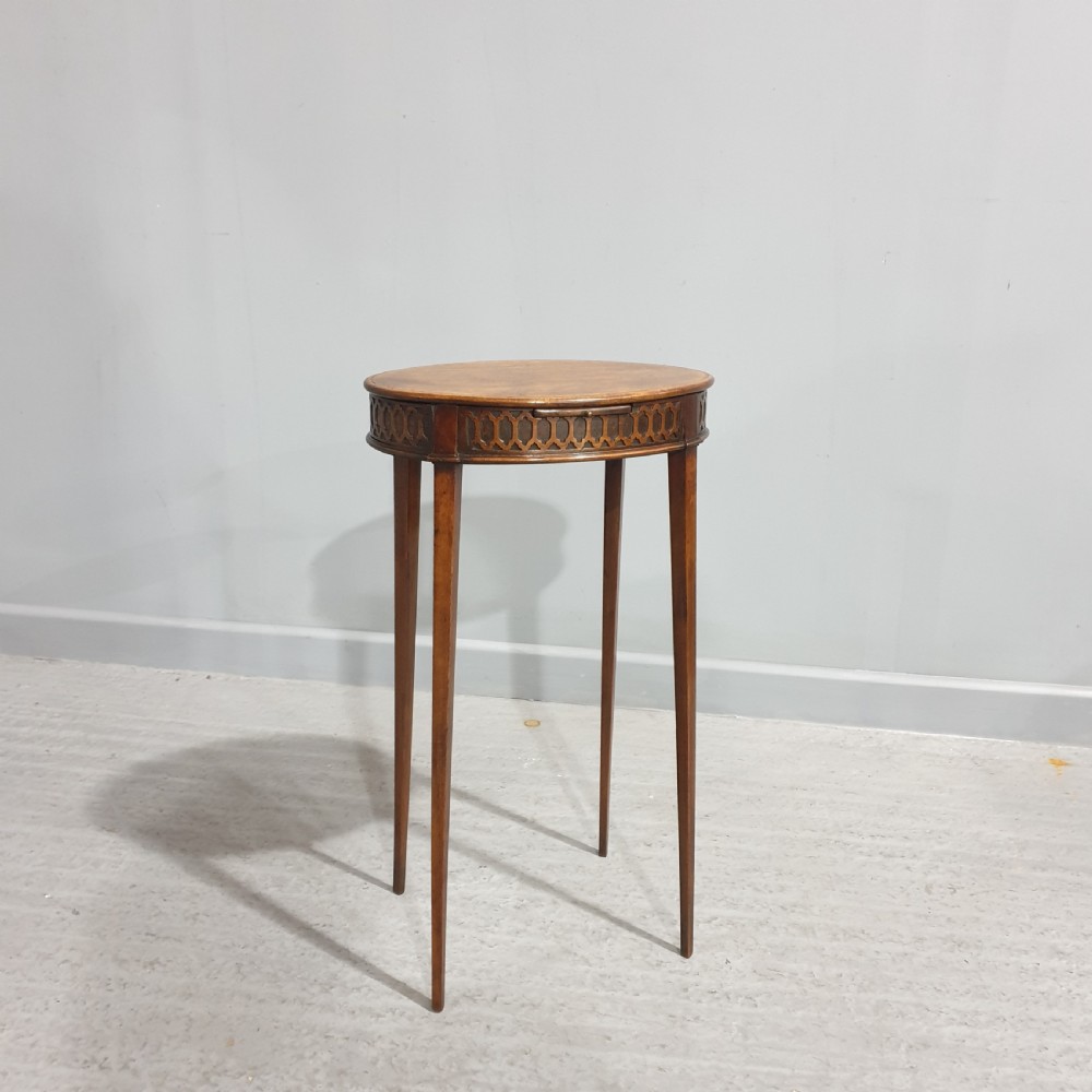 A tall circular mahogany side table featuring a blind fretwork apron and four slender tapered legs.