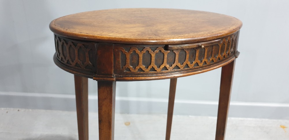 A tall circular mahogany side table featuring a blind fretwork apron and four slender tapered legs. View V
