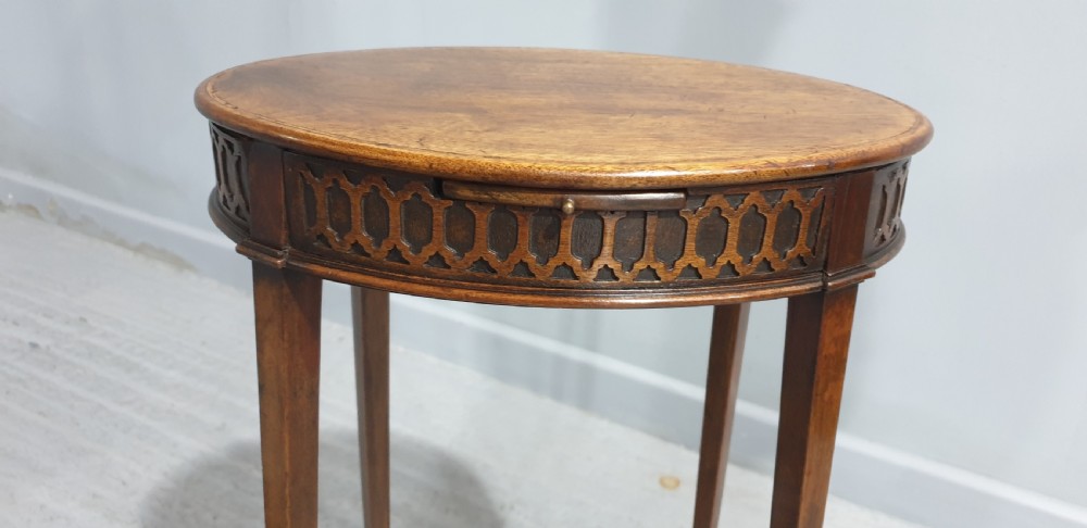 A tall circular mahogany side table featuring a blind fretwork apron and four slender tapered legs. View VI