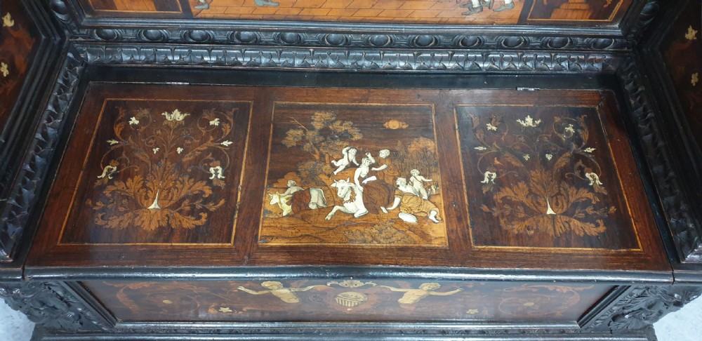 A heavily carved dark walnut Italian hall bench featuring a high backrest with intricate pictorial wood marquetry, winged griffin cresting, and lion paw feet. View IV