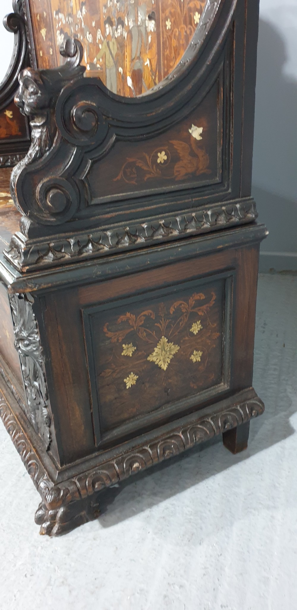 A heavily carved dark walnut Italian hall bench featuring a high backrest with intricate pictorial wood marquetry, winged griffin cresting, and lion paw feet. View VII