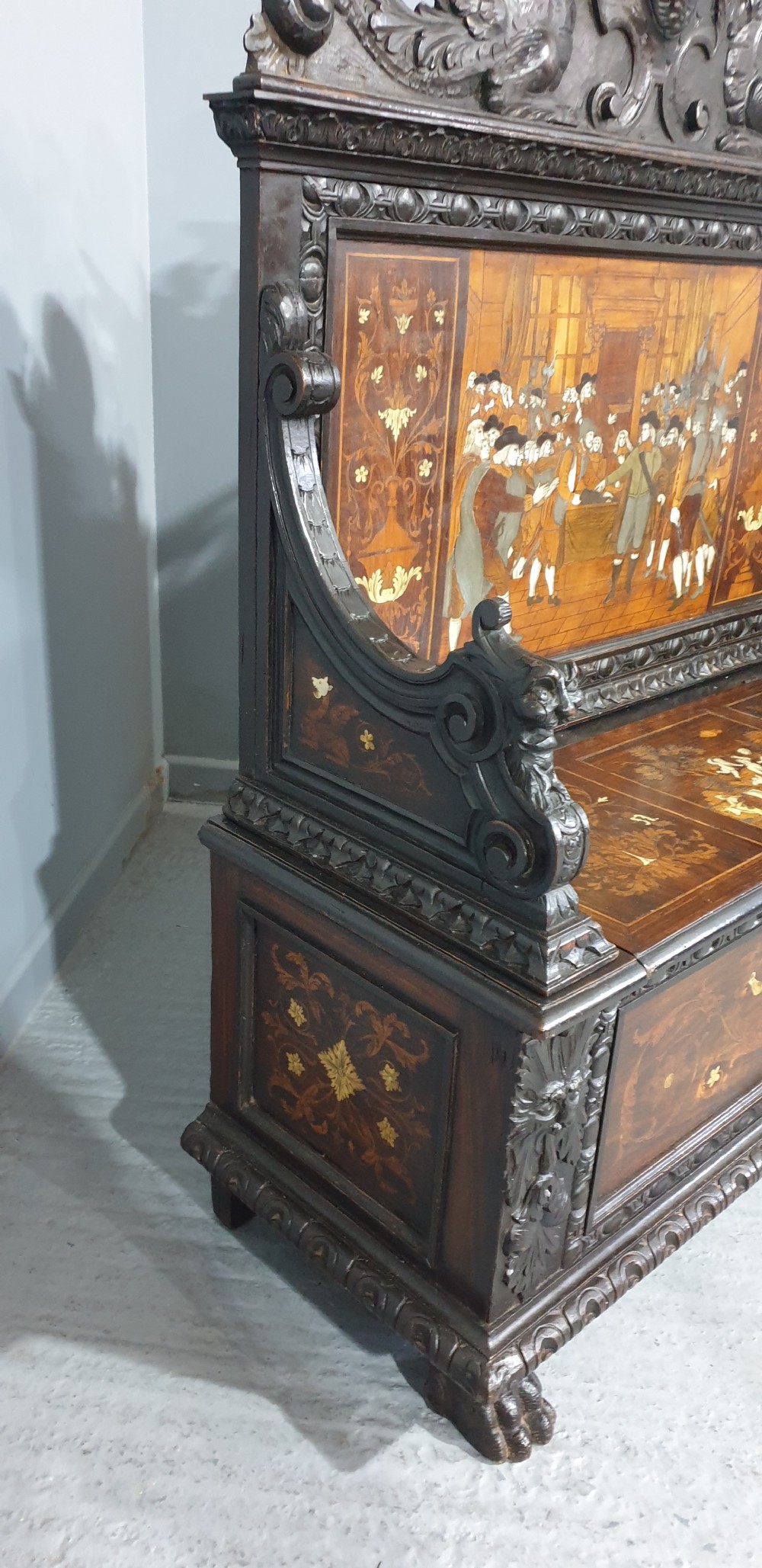 A heavily carved dark walnut Italian hall bench featuring a high backrest with intricate pictorial wood marquetry, winged griffin cresting, and lion paw feet. View VIII
