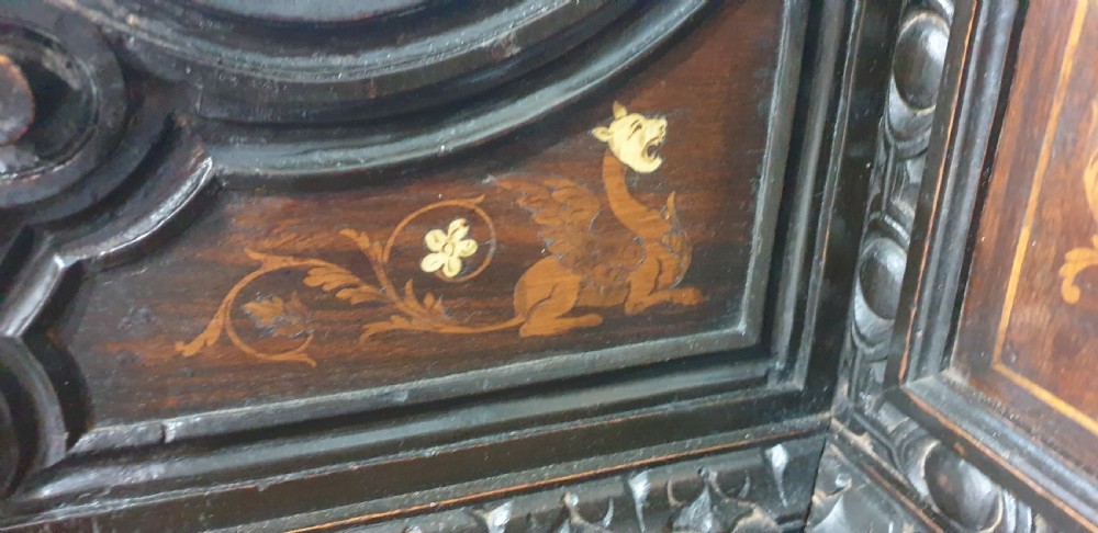 A heavily carved dark walnut Italian hall bench featuring a high backrest with intricate pictorial wood marquetry, winged griffin cresting, and lion paw feet. View XIII