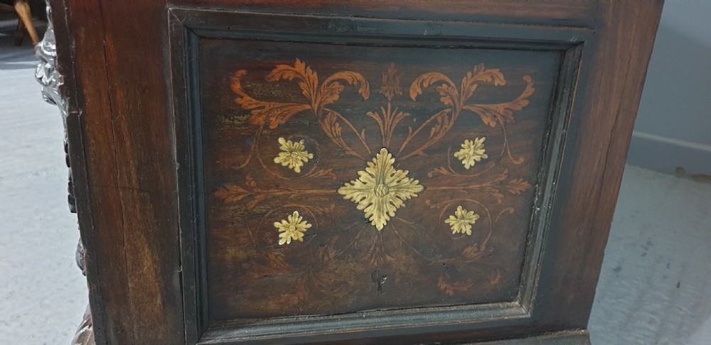 A heavily carved dark walnut Italian hall bench featuring a high backrest with intricate pictorial wood marquetry, winged griffin cresting, and lion paw feet. View XIV