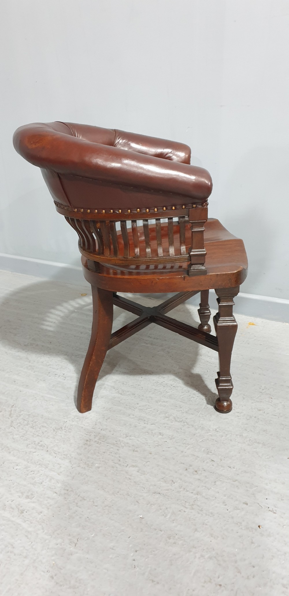Victorian mahogany desk chair with a deep buttoned brown leather horseshoe backrest, slatted gallery, shaped solid timber seat, and X-frame cross stretchers. View III