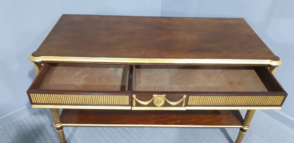 A dark mahogany rectangular console table featuring giltwood fluted legs, a lower shelf, and gold carved swags along the front apron. View XIX