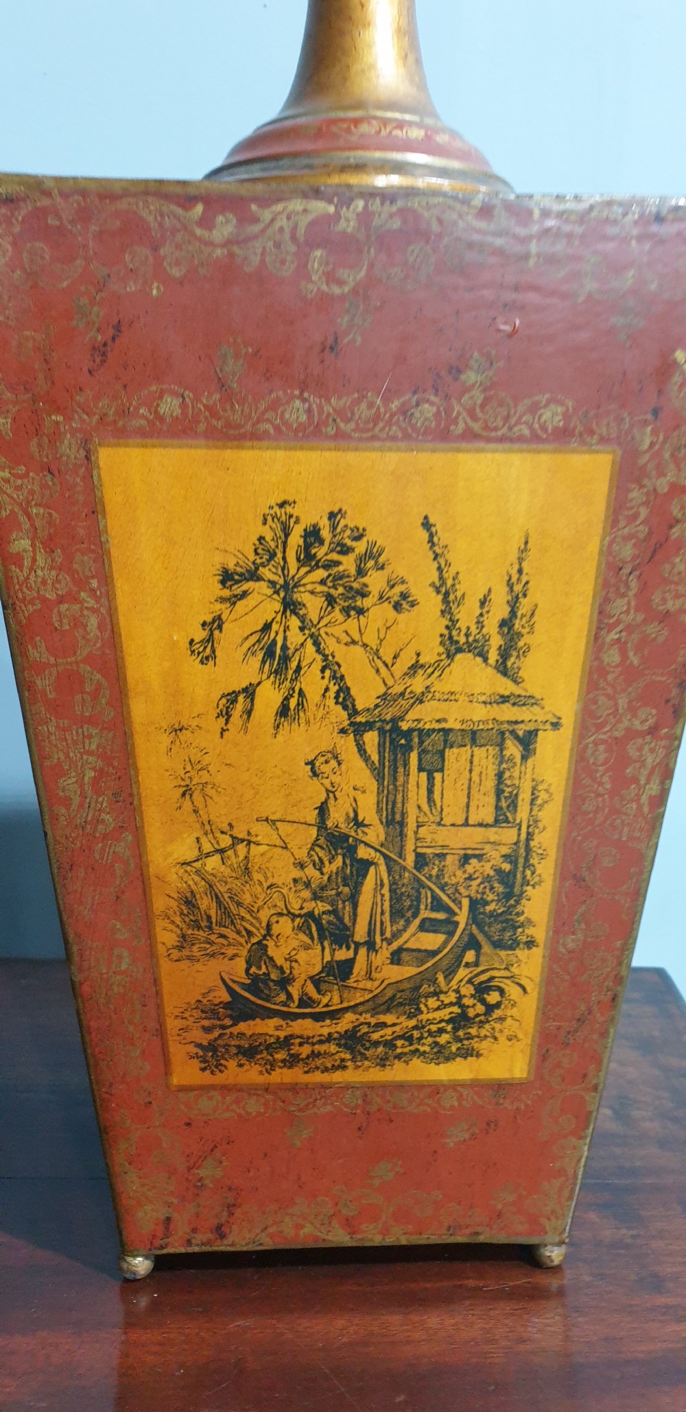 A pair of tapered rectangular red and gold lacquered toleware table lamps decorated with hand-painted chinoiserie figures and brass fittings. View III