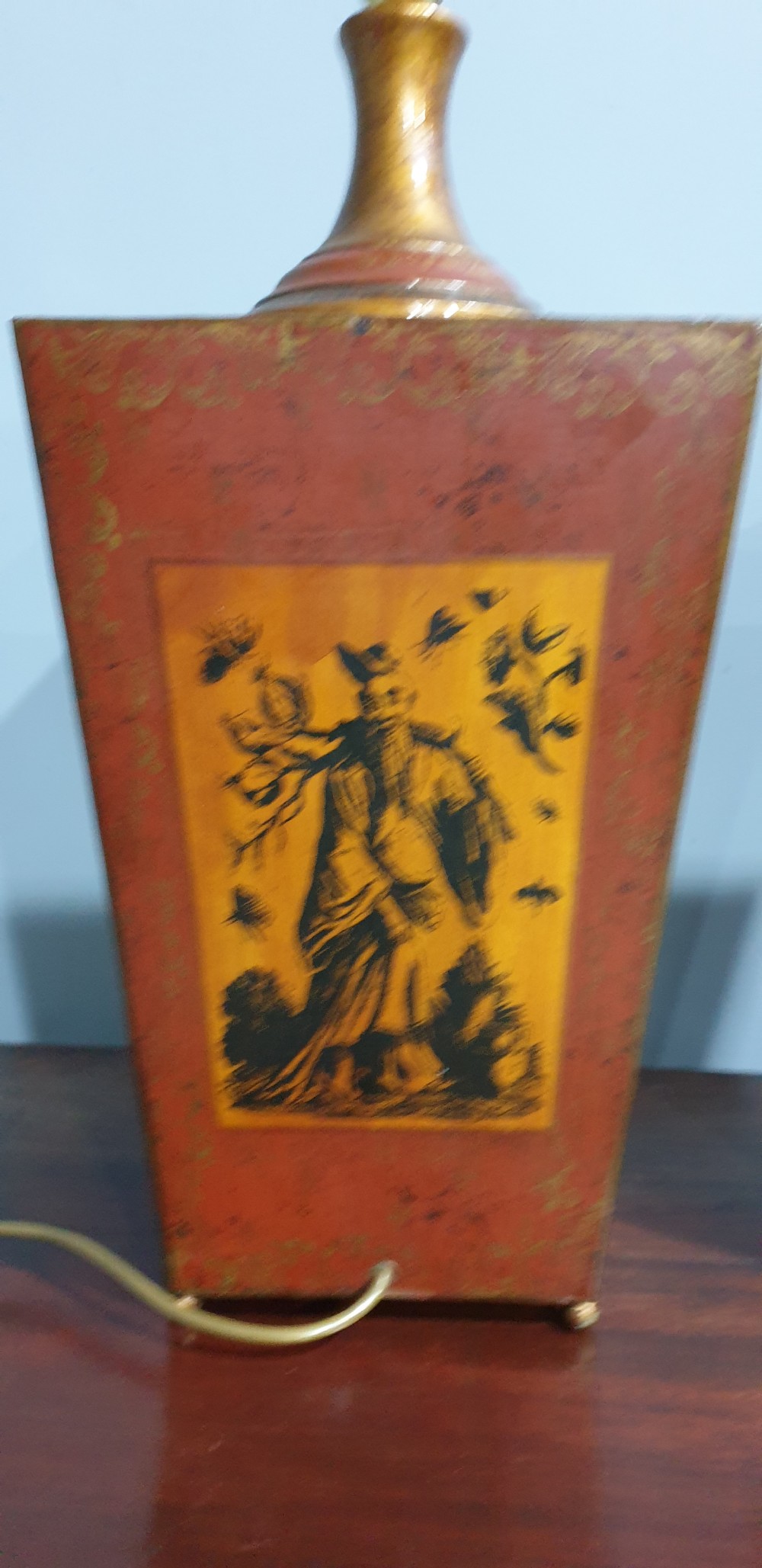 A pair of tapered rectangular red and gold lacquered toleware table lamps decorated with hand-painted chinoiserie figures and brass fittings. View V