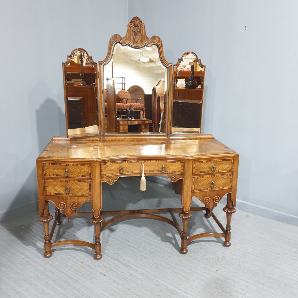 An Edwardian wooden dressing table featuring herringbone parquetry veneers, five drawers, carved legs with a curved stretcher, and an adjustable triple mirror.
