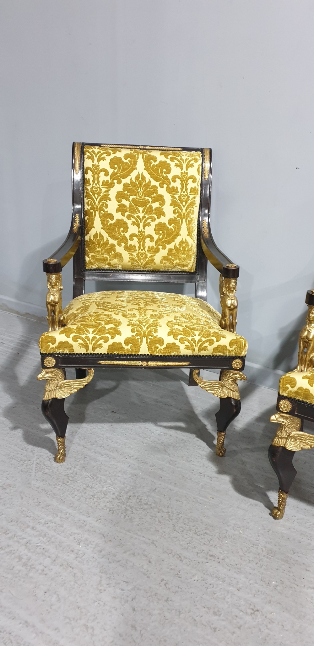 A pair of French Empire armchairs crafted with dark ebonised frames, gilded ormolu caryatid mounts, and patterned gold damask upholstery. View III
