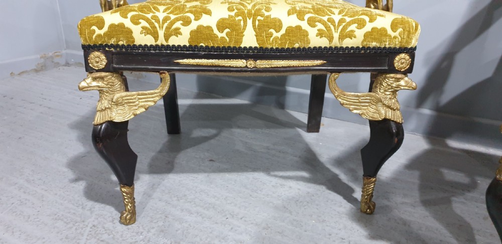 A pair of French Empire armchairs crafted with dark ebonised frames, gilded ormolu caryatid mounts, and patterned gold damask upholstery. View IV